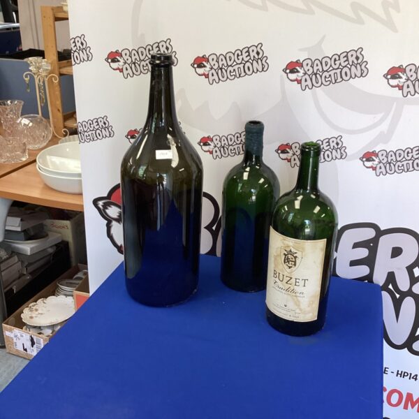 Lot of three dark green empty wine bottles for display.
