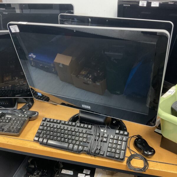 Stone all-in-one computer with keyboard and mouse on a desk.
