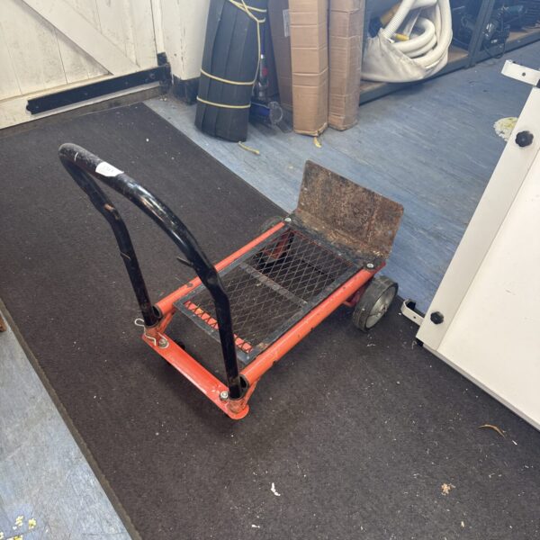 Red sack barrow with black handle on a dark rug.