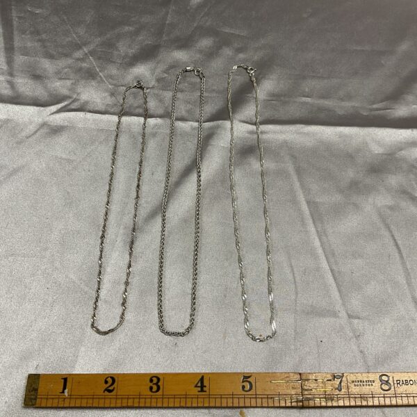 Three delicate 925 silver chain necklaces displayed on a surface.