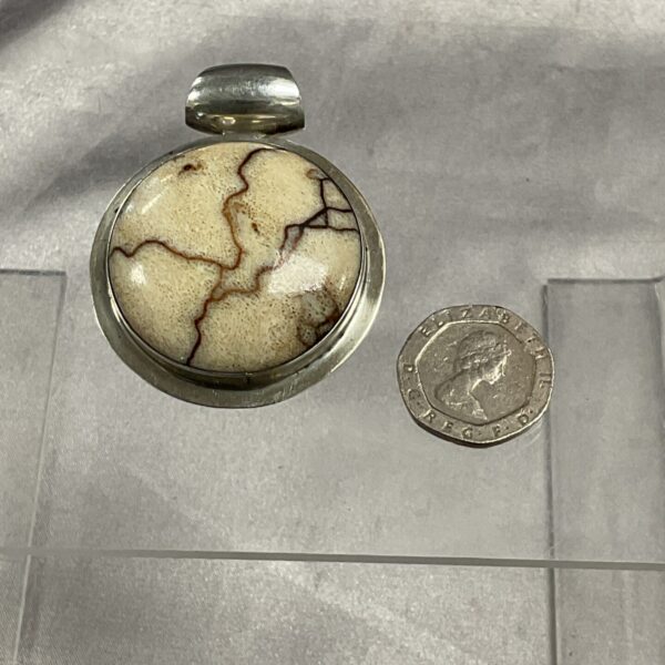 Close-up of a vintage silver marble pendant with swirling stone.