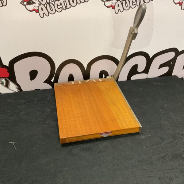 Vintage paper guillotine with wooden base and metal blade.