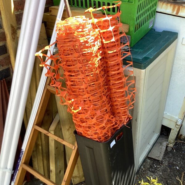 Bright orange roll of temporary plastic fencing for safety.
