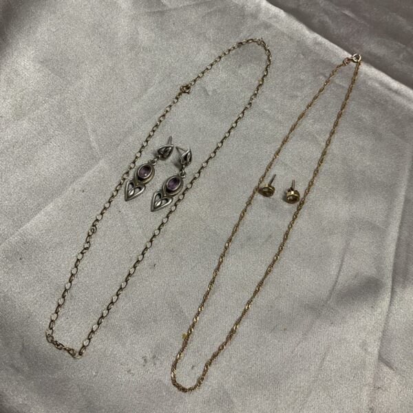 Close-up of 9ct gold chain necklaces and silver earrings jewellery lot.