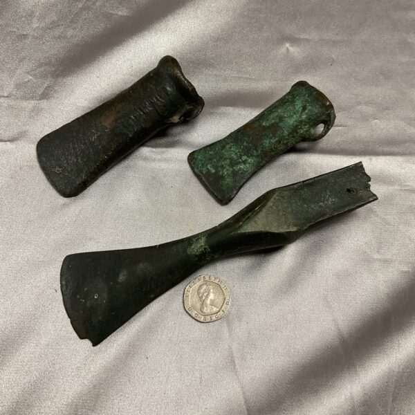 Three antique bronze axe heads with patina.
