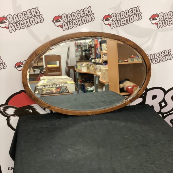 Vintage oval wall mirror with wooden frame for home decor.