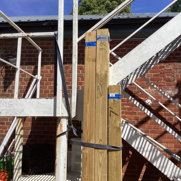 Three bundles of roughly sawn timber stacked outdoors.