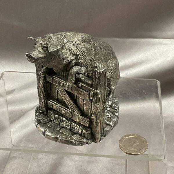 Detailed silver pig figurine leaping over a fence.
