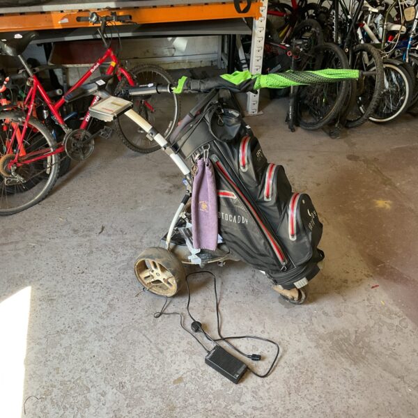 Motocaddy electric golf trolley with power supply and charger.