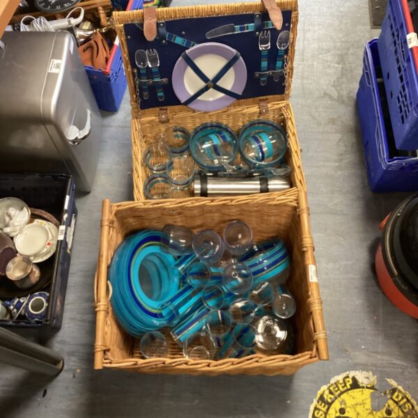 Vintage wicker picnic basket with plastic cups and plates.