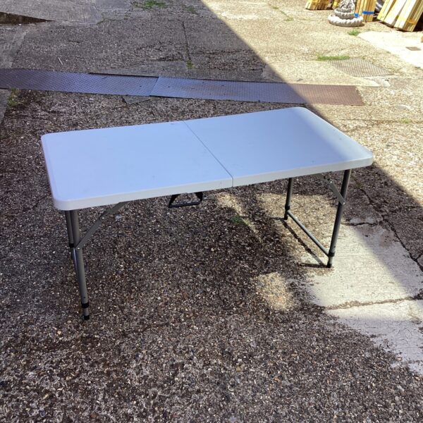 White folding camping table set up outdoors.
