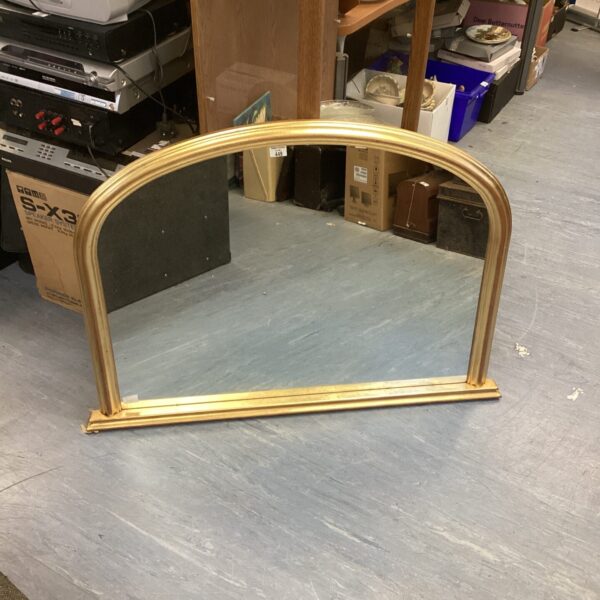 Large gold mantle mirror with ornate frame and arched top.