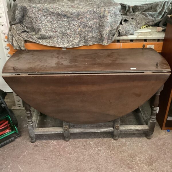 Antique dark wood gate leg table with drop leaf design.
