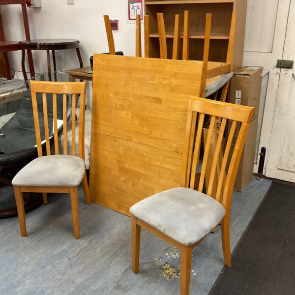 Light oak extending dining table with six chairs in a dining room.