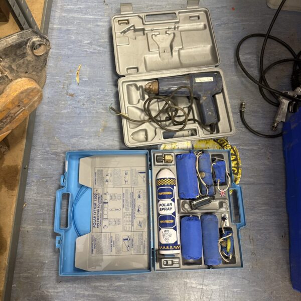 Vintage pipe freezing tool and heat gun kit for plumbing repairs.