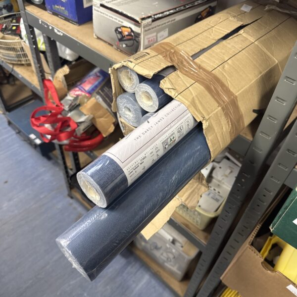 Six rolls of blue linen effect wallpaper stacked together.