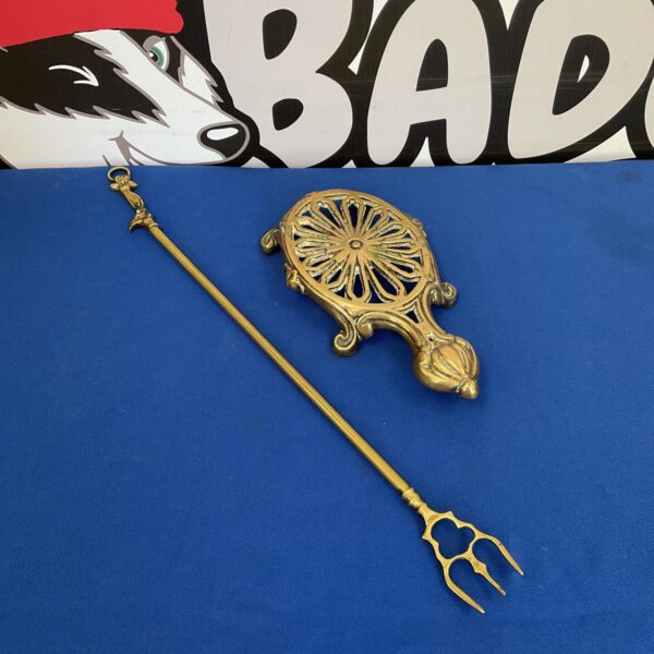 Ornate antique brass trivet with toasting fork, vintage kitchenware.