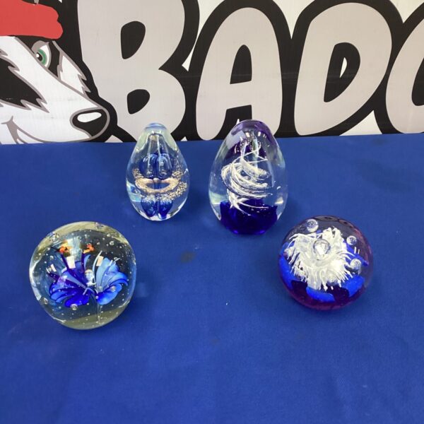 Four colourful Murano glass paperweights displayed together.