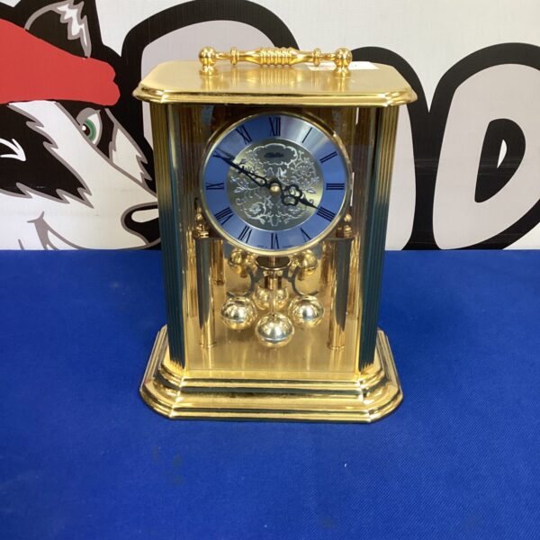 Vintage brass Kaller quartz clock on a dark background.