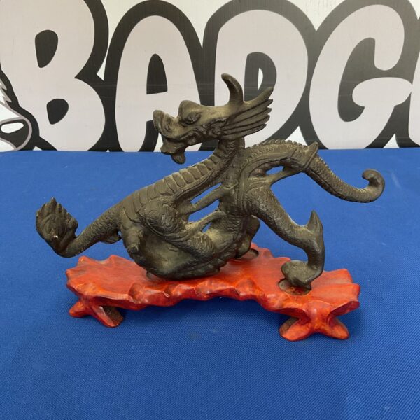 Vintage Chinese bronze dragon statue on wooden stand.