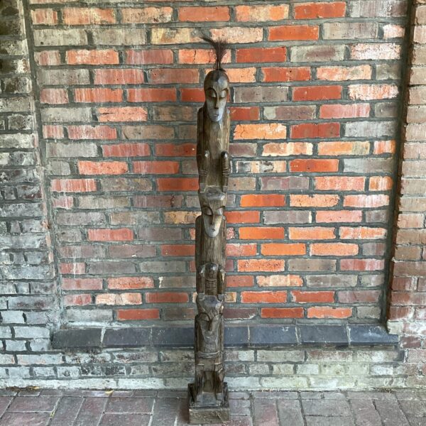 Large carved African tribal totem pole with stacked figures.
