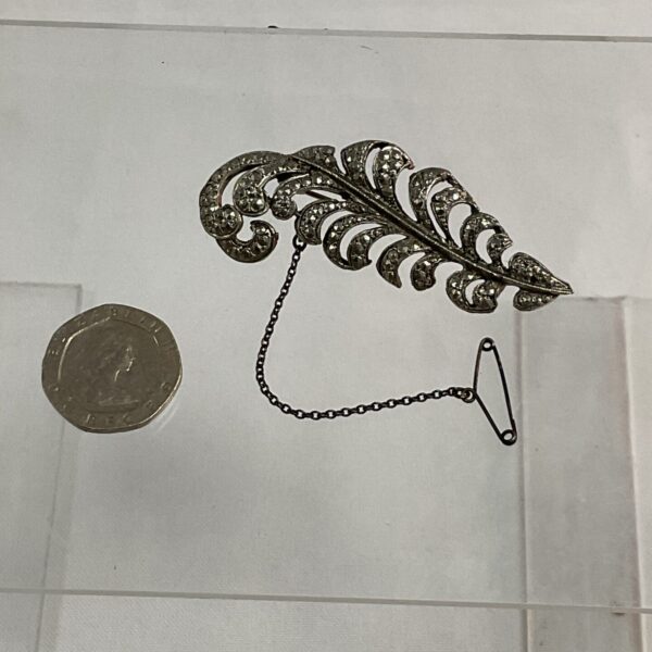 Vintage marcasite feather brooch with a coin for scale.