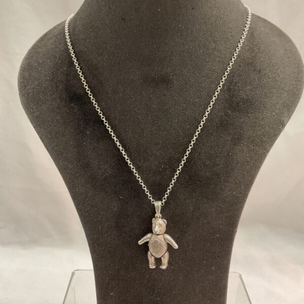 Detailed silver articulated teddy bear pendant on a chain.
