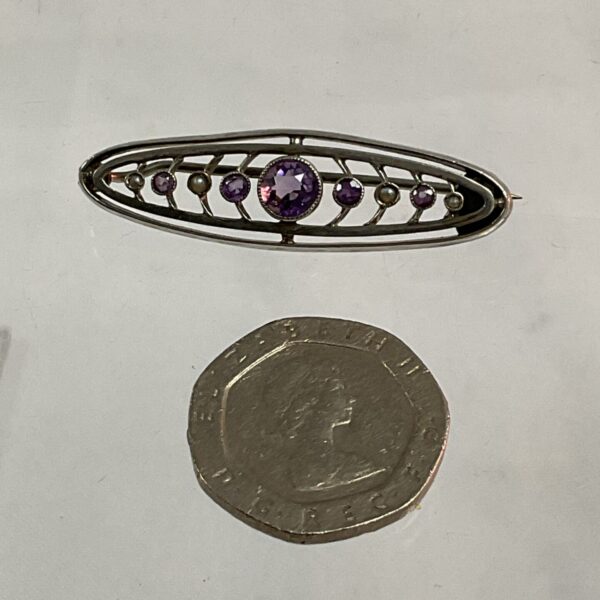 Antique silver brooch with amethyst stones in floral design.