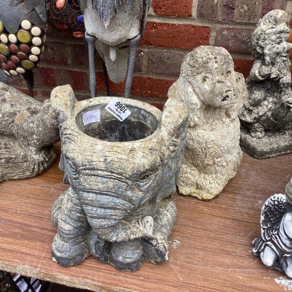 Concrete garden ornaments, an elephant and a poodle, in a garden setting.
