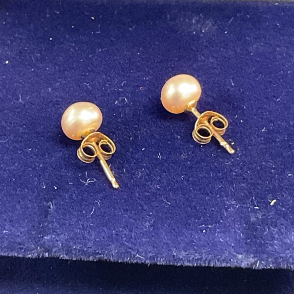 Close-up of 9 carat gold pearl stud earrings with 375 hallmark.