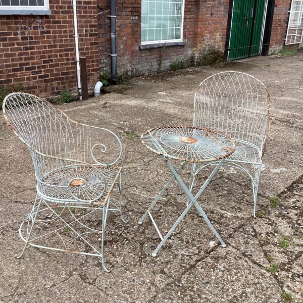Vintage metal garden set with table and two chairs in a garden.