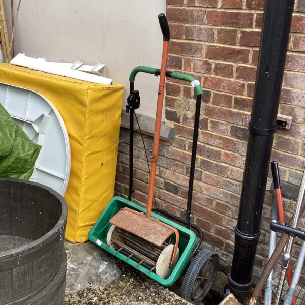 Vintage lawn feeder and spiker in a garden setting.