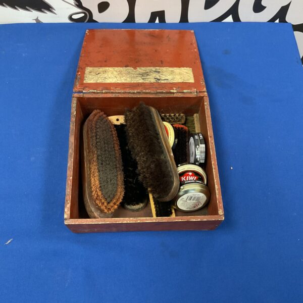 Vintage shoe shining kit in wooden box with brushes and polish.