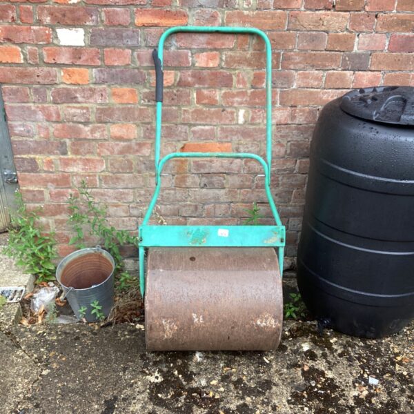 Vintage metal garden roller for lawn maintenance and soil consolidation.