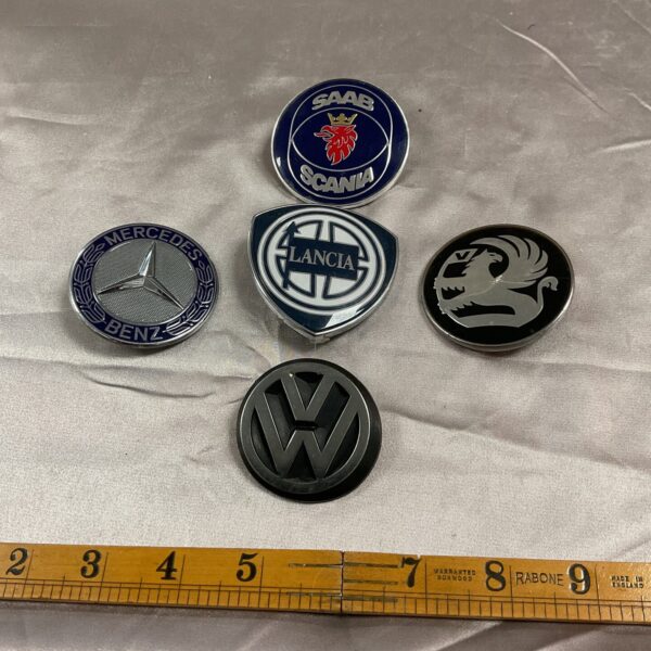 Collection of vintage car badges including Saab and Lancia emblems.