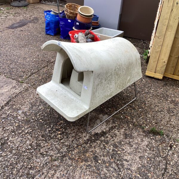 Grey plastic dog house with step in a garden setting.