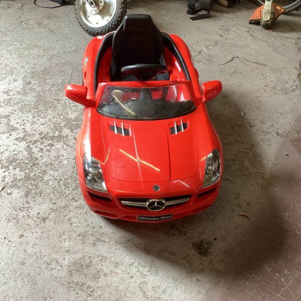 Red Mercedes Benz ride on car for children needing restoration.