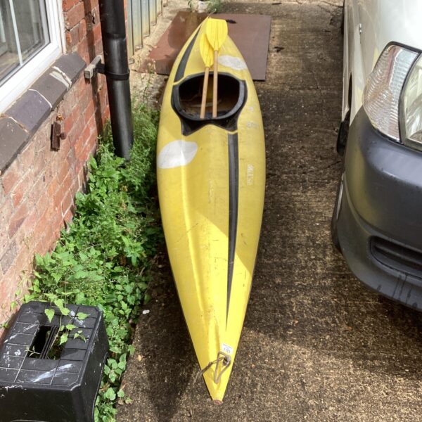 Yellow canoe with paddles in a garden setting.