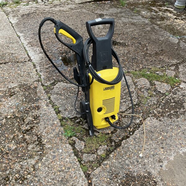 Yellow Karcher pressure washer with handle and attachments.