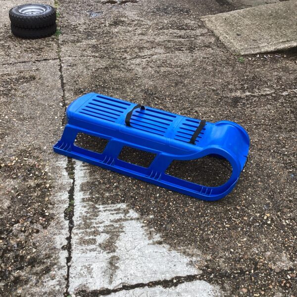 Bright blue plastic grass sledge for outdoor winter and summer fun.