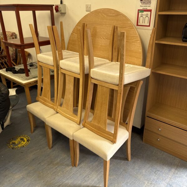 Stacked light oak dining chairs with cream fabric seats.