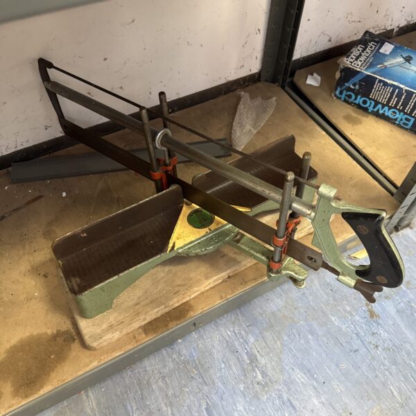 Side view of a vintage mitre saw with metal frame.