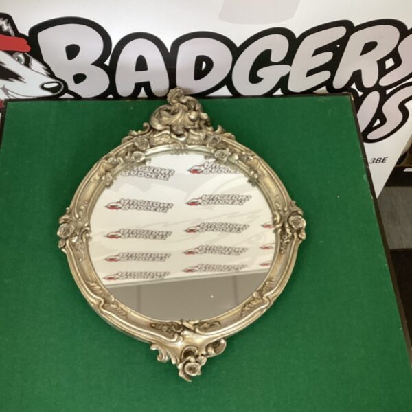 Ornate vintage wall mirror with gilded frame and decorative detailing.