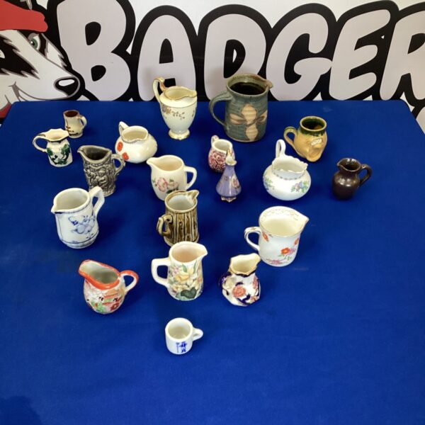 Collection of miniature porcelain and pottery jugs on display.