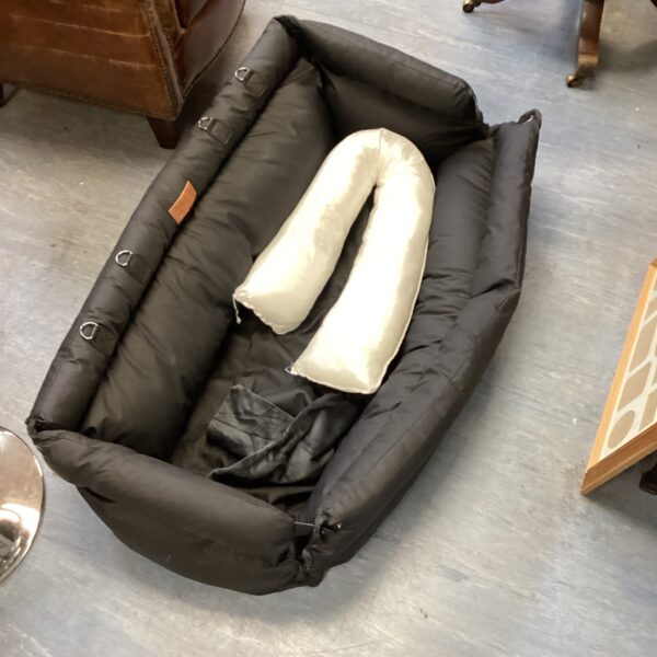 Black fuzzy dog bed with cushioned rim.