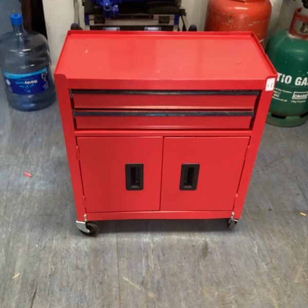 Red metal tool chest on wheels for workshop storage.