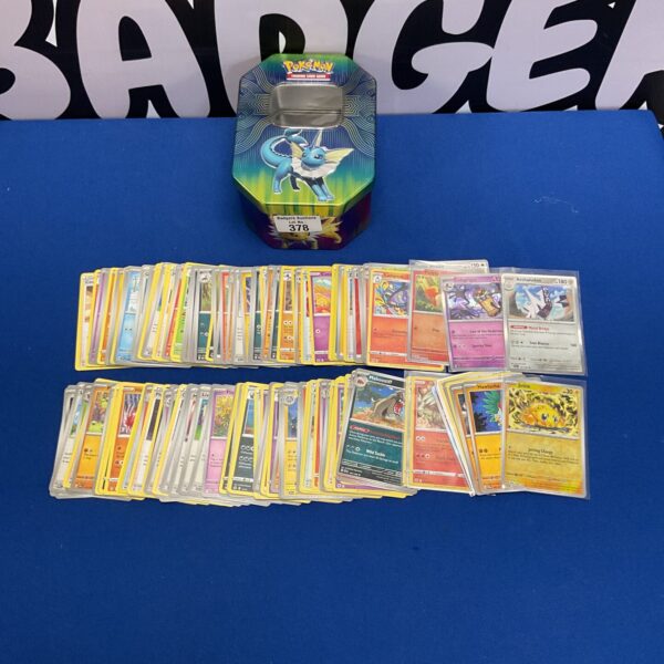 Pokemon card lot with Eevee tin, featuring various cards.