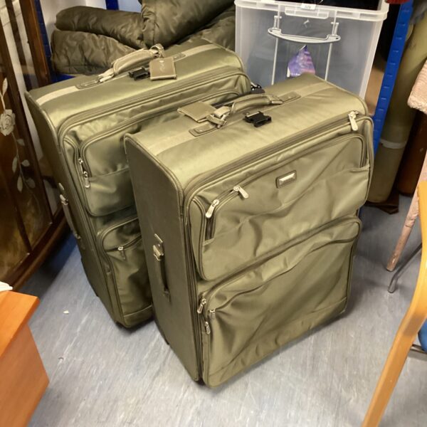 Two large dark green destination suitcases for travel or storage.