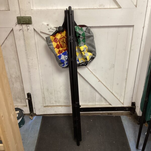 Vintage metal clothing rail with a patterned fabric backdrop.