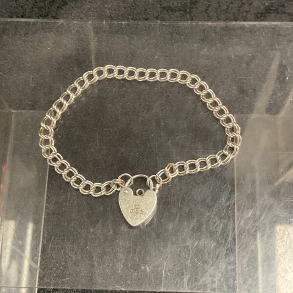 Close-up of silver padlock bracelet with heart charm.